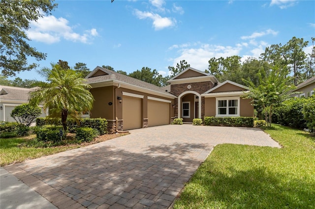 207 Spalding Way, Deland, FL 32724 - ranch-style home with a garage, stucco siding, decorative driveway, a front yard, and stone siding