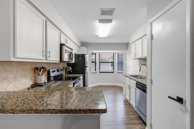 7742 Sugar Bend Dr Unit 7742, Orlando, FL 32819 - kitchen featuring stainless steel appliances, wood finished floors, white cabinetry, and backsplash