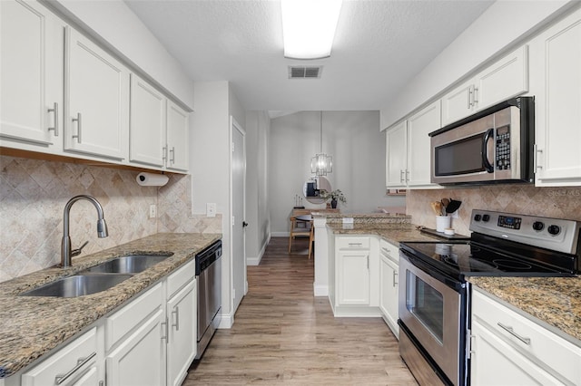 7742 Sugar Bend Dr Unit 7742, Orlando, FL 32819 - kitchen featuring appliances with stainless steel finishes, light wood finished floors, a peninsula, white cabinetry, and a textured ceiling