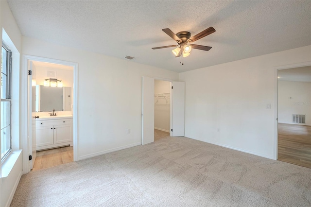 4800 Reginald Rd, Orlando, FL 32829 - unfurnished bedroom featuring light colored carpet, multiple windows, a walk in closet, and a textured ceiling