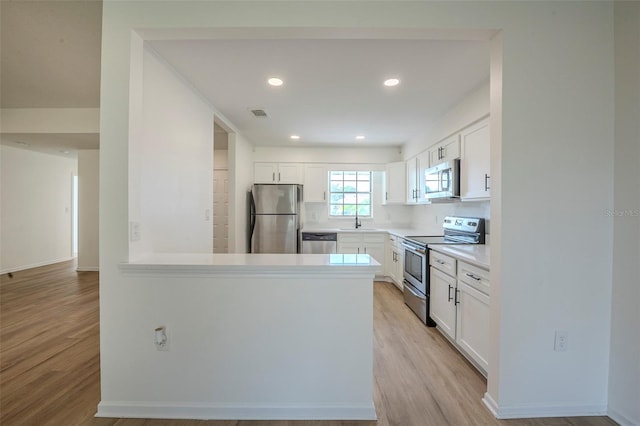 4800 Reginald Rd, Orlando, FL 32829 - kitchen featuring stainless steel appliances, light wood-style flooring, white cabinets, light countertops, and recessed lighting