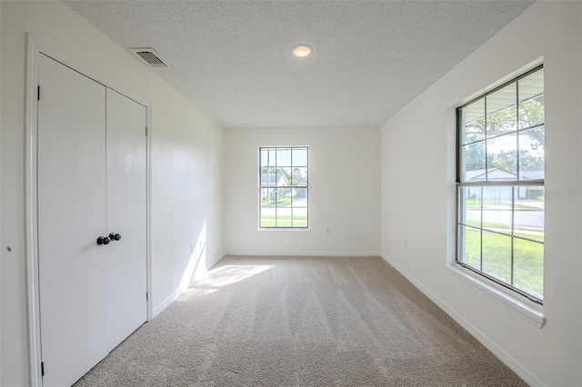 4800 Reginald Rd, Orlando, FL 32829 - unfurnished bedroom with multiple windows, light colored carpet, a textured ceiling, and a closet