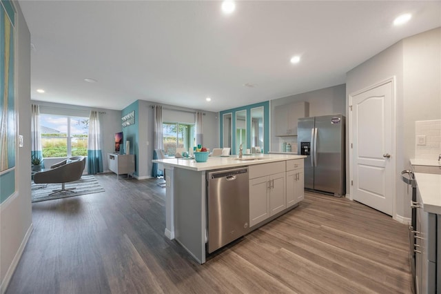 1902 Walnut Creek Dr, Kissimmee, FL 34744 - kitchen with appliances with stainless steel finishes, wood finished floors, light countertops, a kitchen island with sink, and recessed lighting