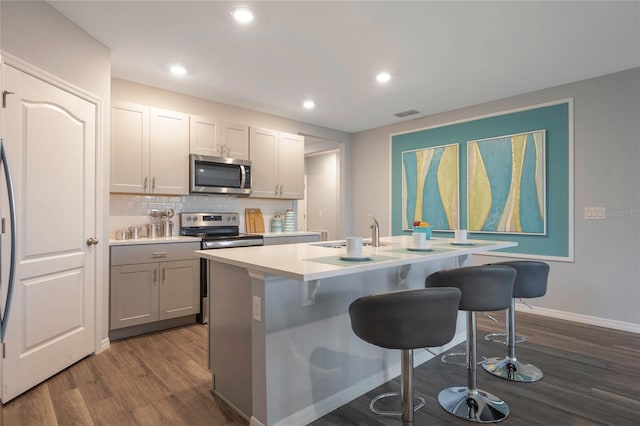 1902 Walnut Creek Dr, Kissimmee, FL 34744 - kitchen featuring stainless steel appliances, dark wood-type flooring, gray cabinetry, a kitchen breakfast bar, and light countertops