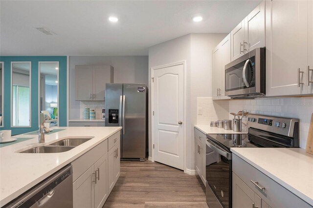 1902 Walnut Creek Dr, Kissimmee, FL 34744 - kitchen featuring appliances with stainless steel finishes, light wood-style flooring, light countertops, decorative backsplash, and recessed lighting