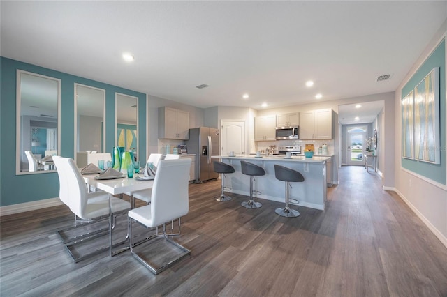 1902 Walnut Creek Dr, Kissimmee, FL 34744 - kitchen with appliances with stainless steel finishes, dark wood-style floors, a kitchen island, light countertops, and a kitchen bar