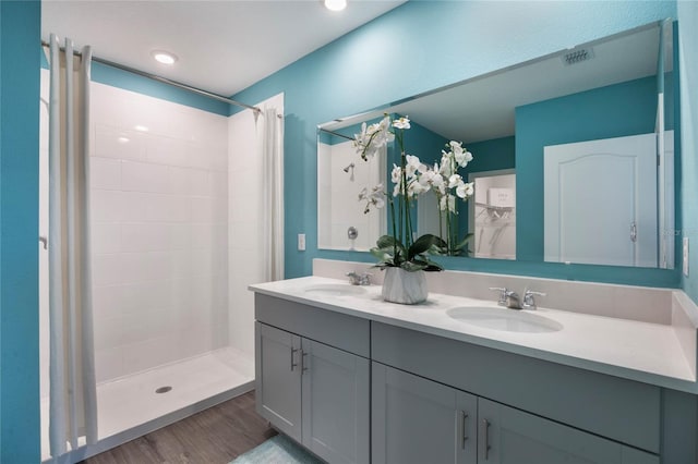1902 Walnut Creek Dr, Kissimmee, FL 34744 - bathroom featuring double vanity, tiled shower, and wood finished floors