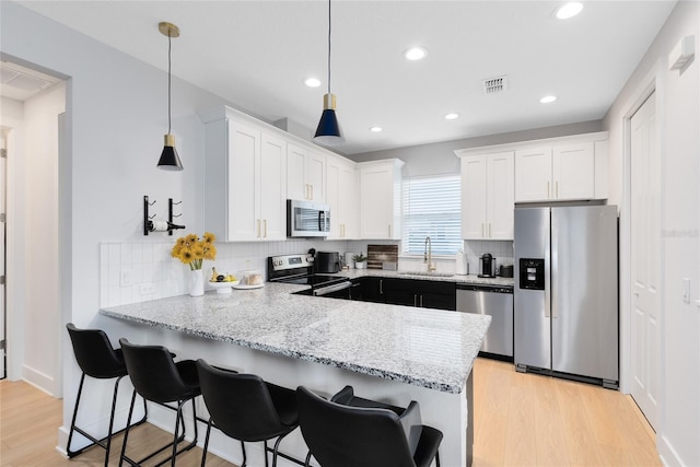 8290 Nemours Pkwy, Orlando, FL 32827 - kitchen with stainless steel appliances, a peninsula, white cabinetry, light wood-style floors, and recessed lighting