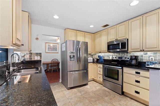 3220 Cardigan Ct, Orlando, FL 32812 - kitchen with appliances with stainless steel finishes, cream cabinetry, decorative backsplash, dark stone countertops, and recessed lighting