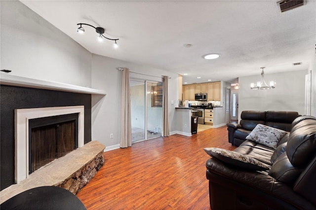 3220 Cardigan Ct, Orlando, FL 32812 - living area featuring wood finished floors, a fireplace with raised hearth, and a chandelier