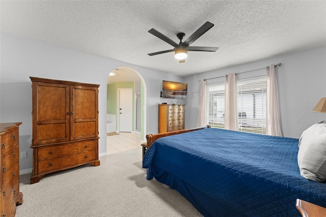 7764 Indian Ridge Trl N, Kissimmee, FL 34747 - bedroom with arched walkways, a textured ceiling, light carpet, a ceiling fan, and ensuite bath