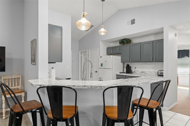7764 Indian Ridge Trl N, Kissimmee, FL 34747 - kitchen featuring freestanding refrigerator, lofted ceiling, a peninsula, a kitchen bar, and hanging light fixtures