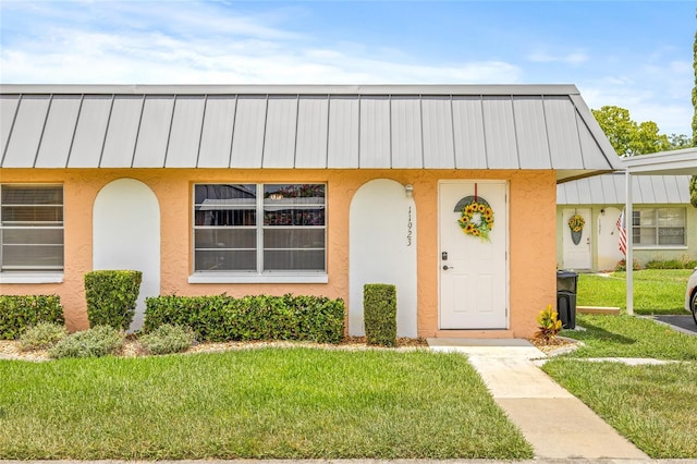 11923 Boynton Ln Unit B, New Port Richey, FL 34654 - view of front of property with a front yard, stucco siding, a standing seam roof, and a metal roof