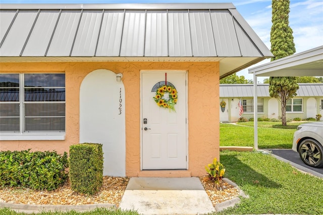11923 Boynton Ln Unit B, New Port Richey, FL 34654 - view of exterior entry with stucco siding, a standing seam roof, and a yard