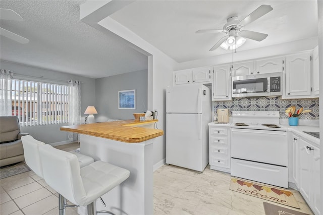 11923 Boynton Ln Unit B, New Port Richey, FL 34654 - kitchen with white appliances, a kitchen bar, a ceiling fan, light countertops, and white cabinetry