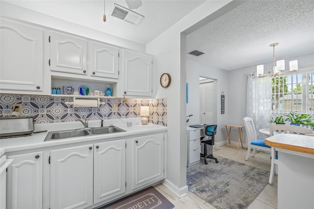 11923 Boynton Ln Unit B, New Port Richey, FL 34654 - kitchen featuring tasteful backsplash, white cabinetry, light countertops, pendant lighting, and a textured ceiling