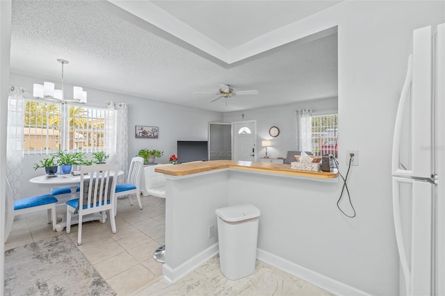 11923 Boynton Ln Unit B, New Port Richey, FL 34654 - kitchen with freestanding refrigerator, a peninsula, a textured ceiling, decorative light fixtures, and ceiling fan