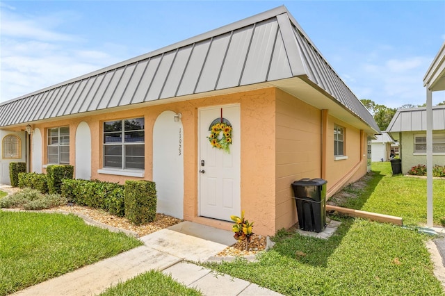 11923 Boynton Ln Unit B, New Port Richey, FL 34654 - view of front of house featuring a standing seam roof, a metal roof, a front yard, and stucco siding
