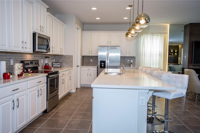 9071 Sunshine Ridge Loop, Kissimmee, FL 34747 - kitchen with stainless steel appliances, dark tile patterned floors, a kitchen bar, white cabinetry, and recessed lighting