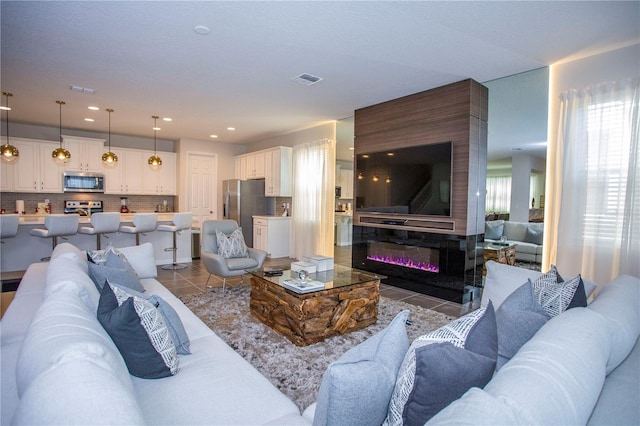 9071 Sunshine Ridge Loop, Kissimmee, FL 34747 - living room featuring light tile patterned flooring, a glass covered fireplace, and recessed lighting