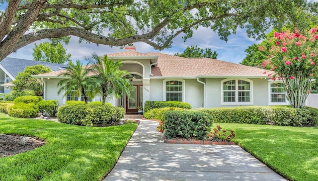 6630 Hidden Beach Cir, Orlando, FL 32819 - view of front of house featuring stucco siding, a front yard, and a chimney