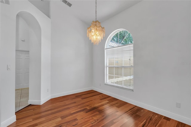 12713 Pine Arbor Dr, Clermont, FL 34711 - spare room featuring wood finished floors, a chandelier, and arched walkways