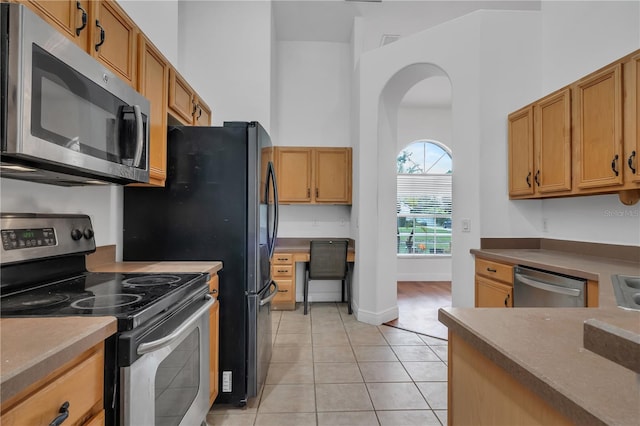 12713 Pine Arbor Dr, Clermont, FL 34711 - kitchen with appliances with stainless steel finishes, arched walkways, light tile patterned floors, and a towering ceiling