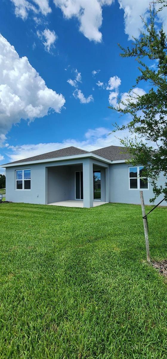 483 Shadow Gorge Way, Eustis, FL 32736 - rear view of house featuring stucco siding and a yard