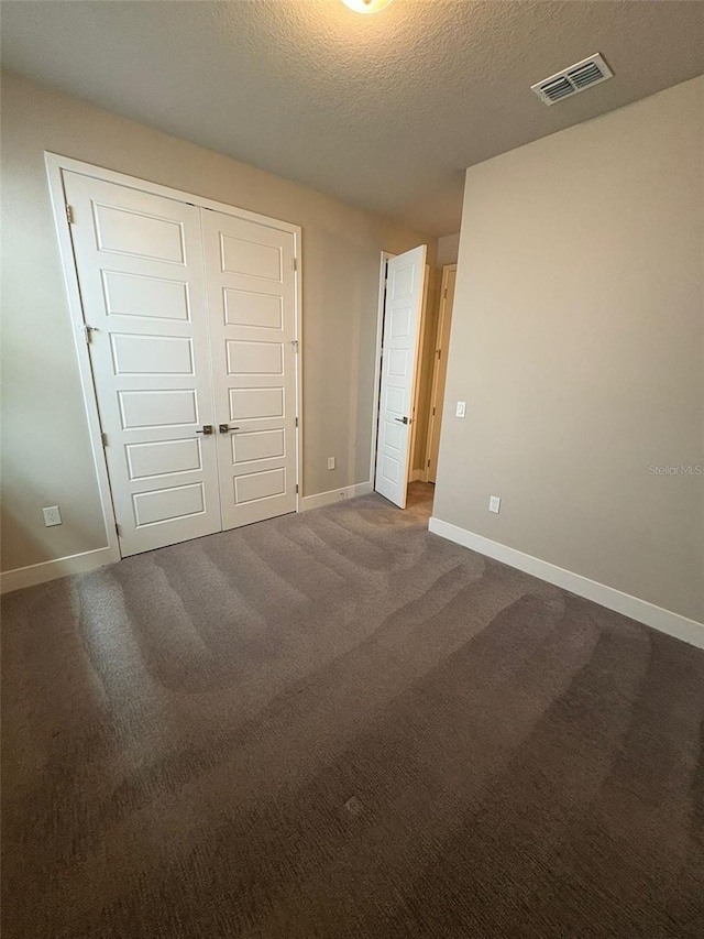 2318 Raven Ridge Rd, Minneola, FL 34715 - unfurnished bedroom with a closet, dark carpet, and a textured ceiling