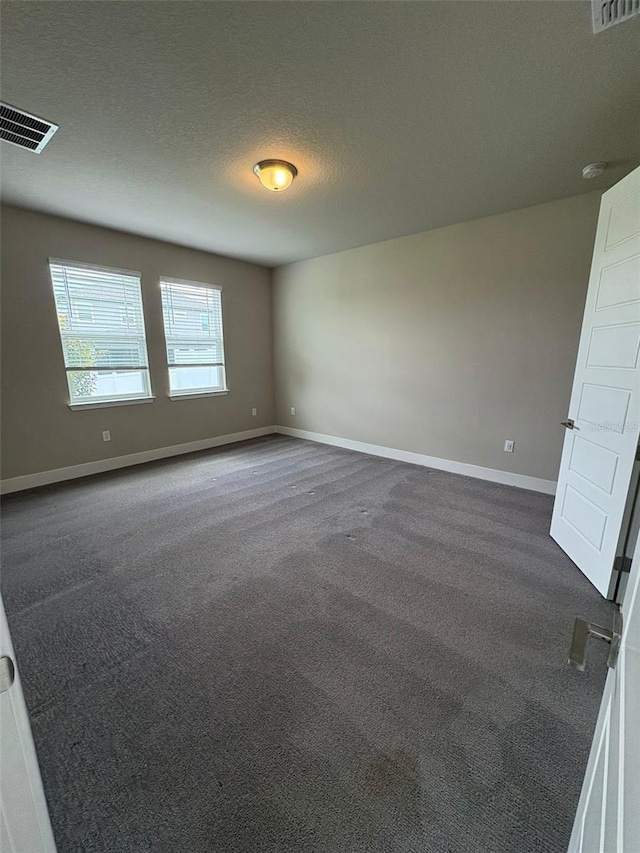 2318 Raven Ridge Rd, Minneola, FL 34715 - unfurnished room with dark colored carpet, a textured ceiling, and a smoke detector