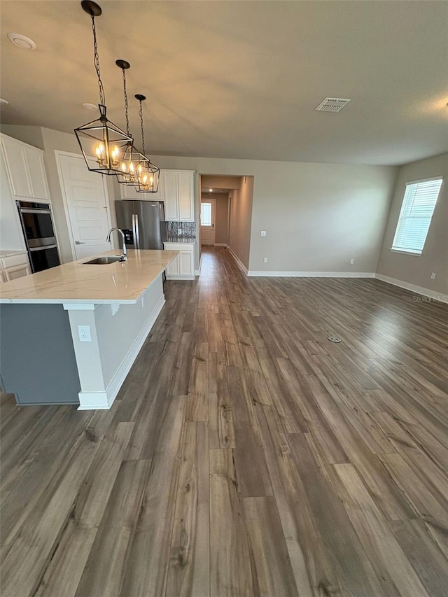 2318 Raven Ridge Rd, Minneola, FL 34715 - kitchen featuring appliances with stainless steel finishes, white cabinetry, dark wood-type flooring, a large island, and pendant lighting