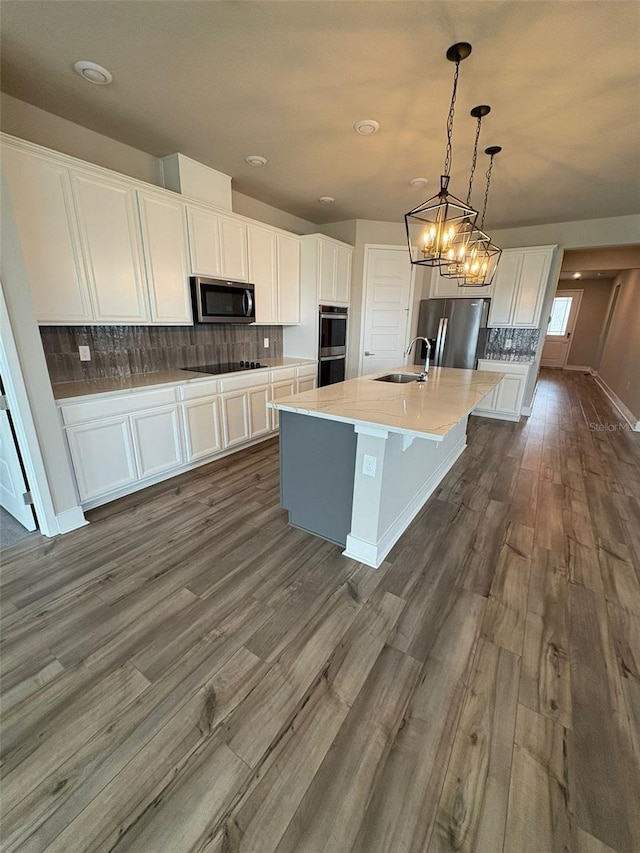 2318 Raven Ridge Rd, Minneola, FL 34715 - kitchen with stainless steel appliances, white cabinets, dark wood-style flooring, tasteful backsplash, and a kitchen island with sink