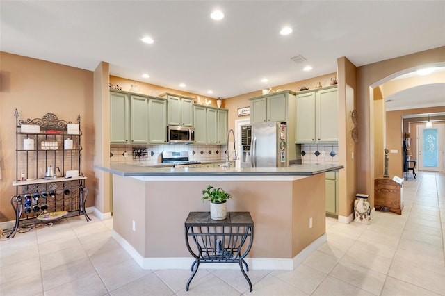 5263 Beach River Rd, Windermere, FL 34786 - kitchen featuring appliances with stainless steel finishes, arched walkways, green cabinets, backsplash, and recessed lighting