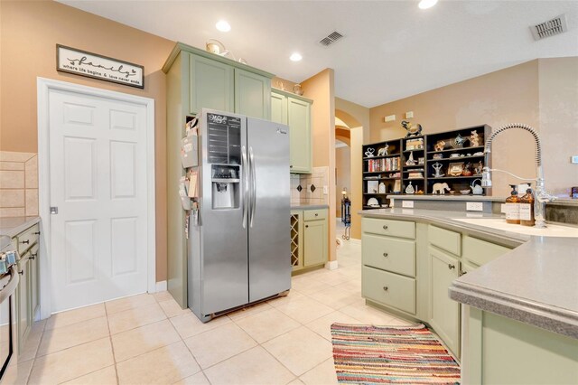 5263 Beach River Rd, Windermere, FL 34786 - kitchen featuring stainless steel fridge with ice dispenser, green cabinetry, decorative backsplash, light tile patterned floors, and arched walkways