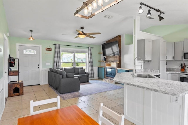 705 Ibis Ave, Deltona, FL 32738 - kitchen with white microwave, lofted ceiling, rail lighting, light tile patterned floors, and a peninsula