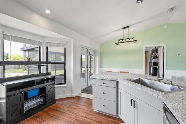 705 Ibis Ave, Deltona, FL 32738 - kitchen featuring vaulted ceiling, stainless steel dishwasher, wood finished floors, plenty of natural light, and white cabinetry