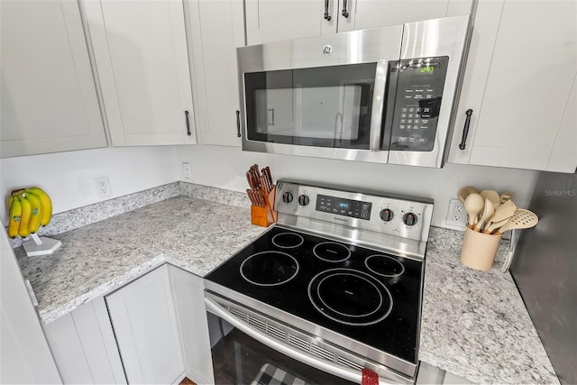 705 Ibis Ave, Deltona, FL 32738 - kitchen with stainless steel appliances, white cabinets, and light stone counters