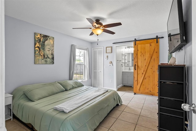 705 Ibis Ave, Deltona, FL 32738 - bedroom with light tile patterned floors, a barn door, a closet, ensuite bath, and ceiling fan