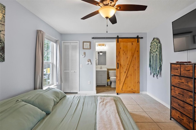705 Ibis Ave, Deltona, FL 32738 - bedroom with a barn door, a closet, ensuite bath, light tile patterned floors, and a ceiling fan