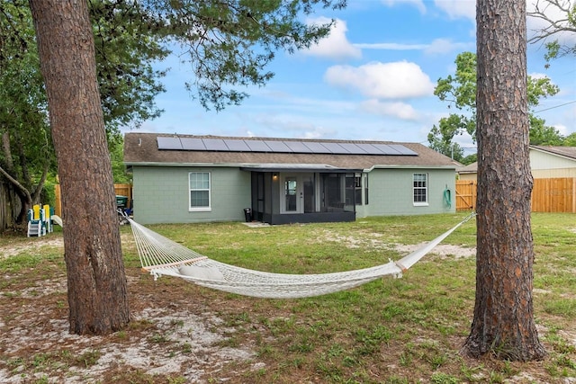 705 Ibis Ave, Deltona, FL 32738 - back of house with concrete block siding, a sunroom, solar panels, and roof with shingles