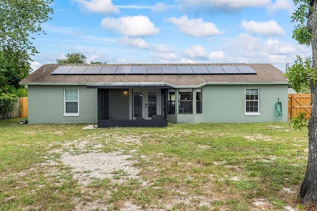 705 Ibis Ave, Deltona, FL 32738 - back of house featuring concrete block siding, a sunroom, roof with shingles, and solar panels
