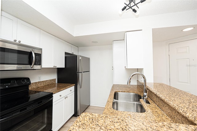 5160 Conroy Rd Unit 21, Orlando, FL 32811 - kitchen featuring appliances with stainless steel finishes, white cabinets, light wood-style flooring, recessed lighting, and light stone counters