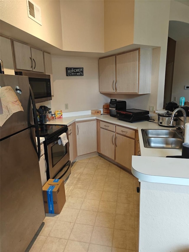 7230 Westpointe Blvd Unit 1235, Orlando, FL 32835 - kitchen with appliances with stainless steel finishes, light brown cabinets, light countertops, a peninsula, and a high ceiling