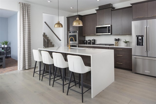 2374 Celebration Blvd, Celebration, FL 34747 - kitchen with stainless steel appliances, recessed lighting, a kitchen island with sink, light wood finished floors, and a breakfast bar area
