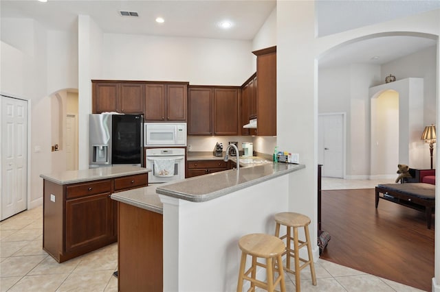 1542 Wescott Loop, Winter Springs, FL 32708 - kitchen featuring white appliances, a high ceiling, light tile patterned floors, a kitchen breakfast bar, and a peninsula