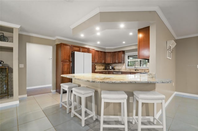 209 7th St S, Haines City, FL 33844 - kitchen with freestanding refrigerator, a peninsula, light stone counters, light tile patterned flooring, and recessed lighting