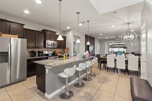 2121 Morocco Way, Kissimmee, FL 34747 - kitchen with appliances with stainless steel finishes, dark brown cabinets, light tile patterned flooring, backsplash, and open floor plan