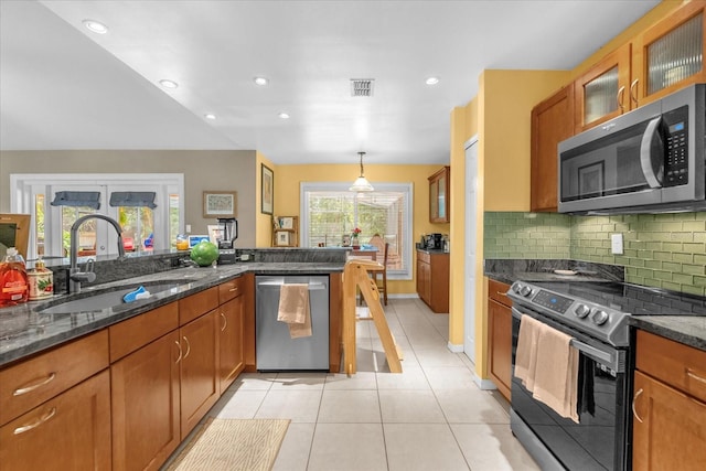 9275 Lake Sharp Ct, Orlando, FL 32817 - kitchen featuring stainless steel appliances, brown cabinets, light tile patterned floors, backsplash, and recessed lighting