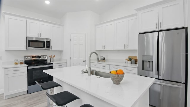17 Cypress Run, Haines City, FL 33844 - kitchen featuring stainless steel appliances, white cabinetry, light countertops, light wood-type flooring, and a kitchen bar