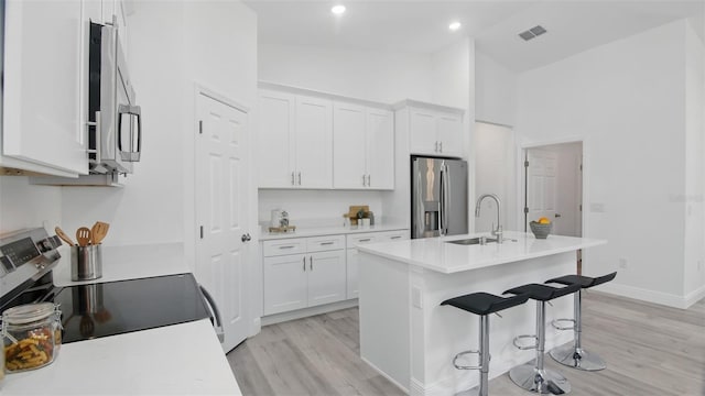 17 Cypress Run, Haines City, FL 33844 - kitchen featuring appliances with stainless steel finishes, light wood-style flooring, white cabinets, a kitchen bar, and high vaulted ceiling